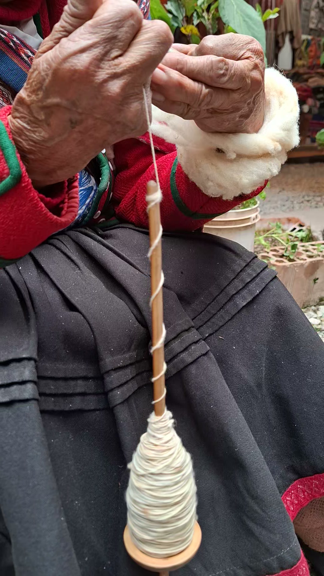 Una mano hace girar el huso mientras se forma el hilo