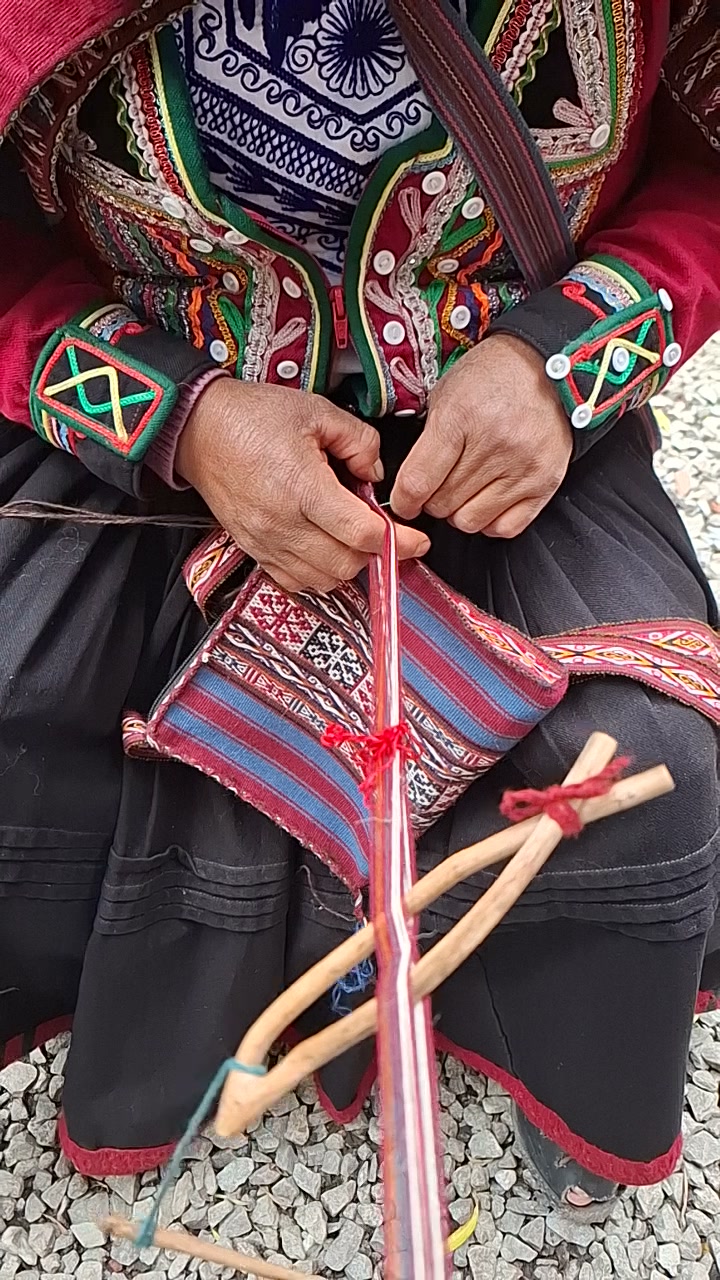 Manos trabajando un tejido en un telar de cintura